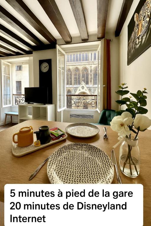 une salle à manger avec une table avec un vase de fleurs dans l'établissement Appartement Vue Cathédrale- Centre ville Meaux-Gare-Disney, à Meaux