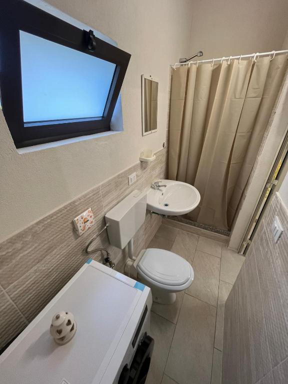 un bagno con un water, un lavandino e una finestra di camping Venere a Granelli
