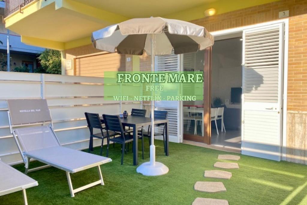 a patio with a table and chairs and an umbrella at NOVELLA DEL MAR prima fila dal mare in Grottammare
