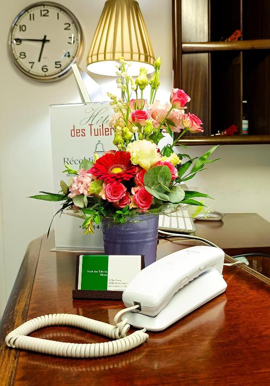 un téléphone et un bouquet de fleurs sur un bureau dans l'établissement Hotel Des Tuileries, à Nîmes
