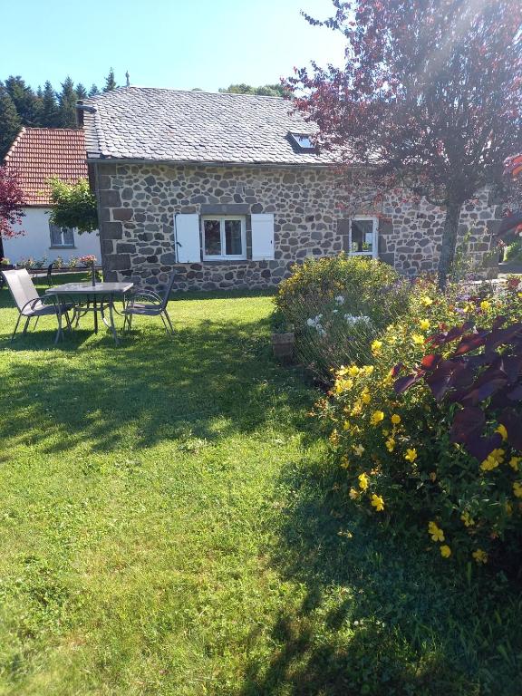 une maison en pierre avec une table et des chaises dans une cour dans l'établissement ferme de Lamourio, à Saint-Cernin