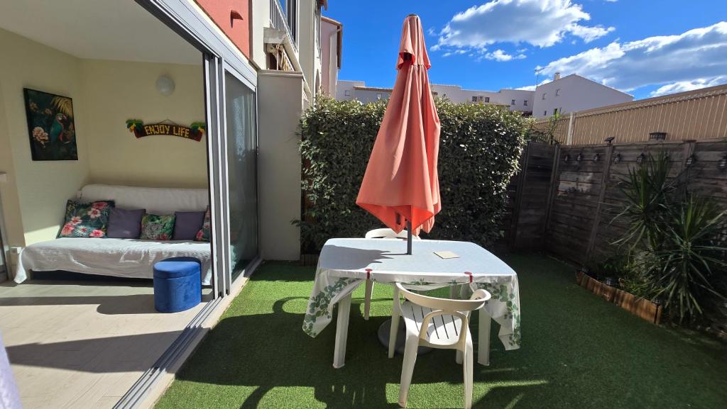 un patio avec un parasol, une table et des chaises dans l'établissement Joli T2 avec jardin plage Richelieu - 6 personnes, au Cap d'Agde