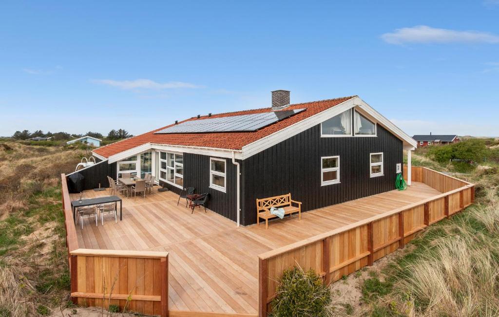 a black house with a deck on the beach at Cozy Home In Hjørring With Sauna in Lønstrup