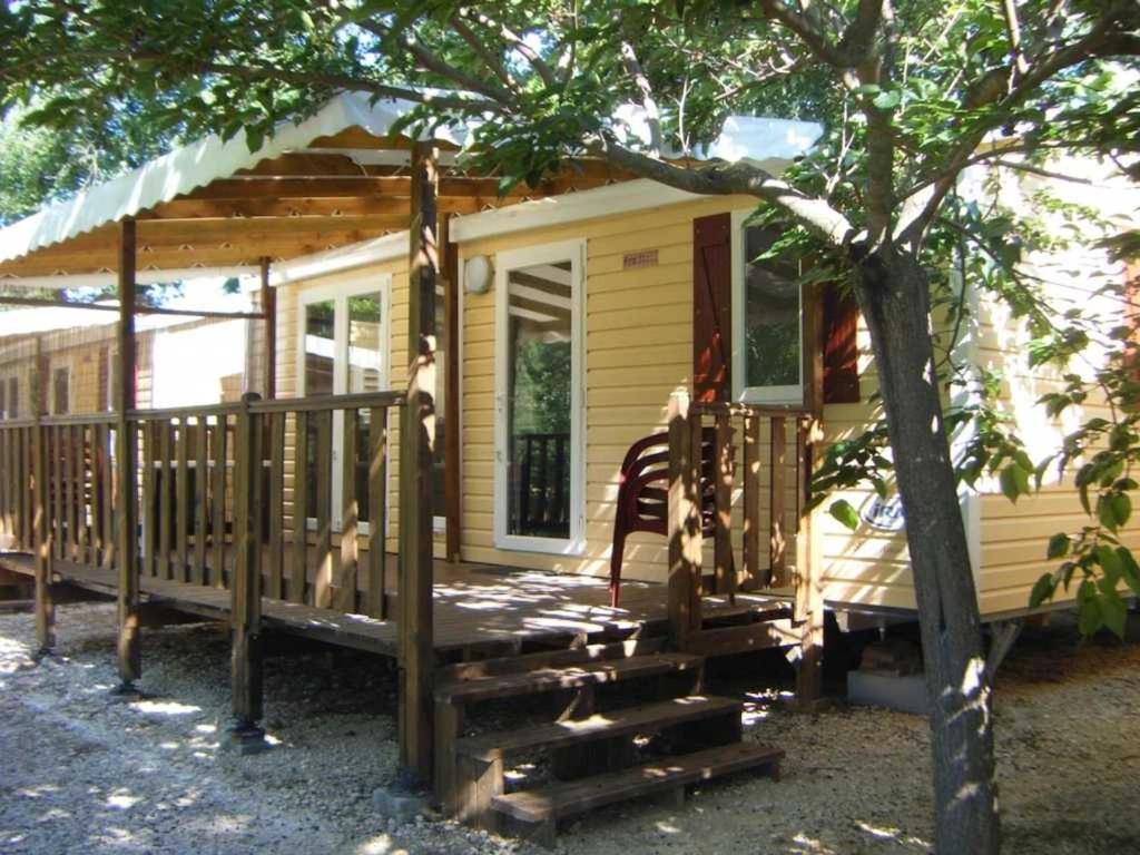 een klein geel huis met een veranda en een boom bij Camping 4 étoiles - Piscine - ccb0dhf in Saint-Denis