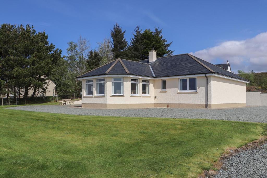 a large white house with a gravel driveway at Riverside Cottage in Portree