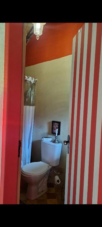 a bathroom with a white toilet and a striped wall at Casinha Messiah in Água Boa
