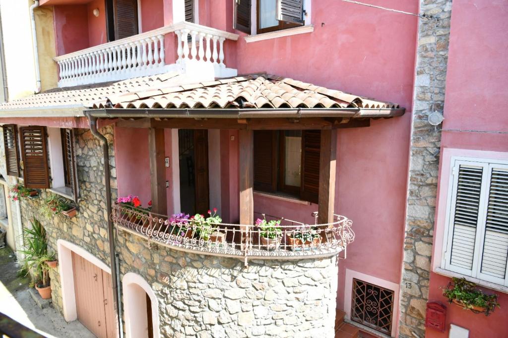 a pink building with a balcony with flowers on it at Da Minnia in Orgosolo