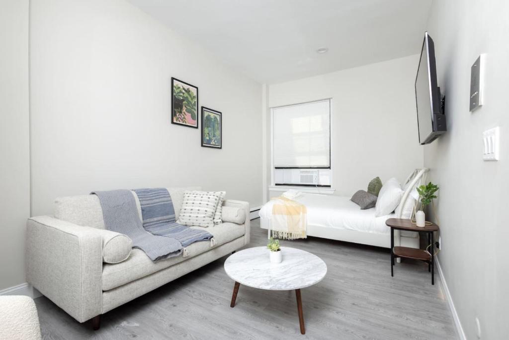a white living room with a couch and a table at Charming South End Studio Apt in Boston