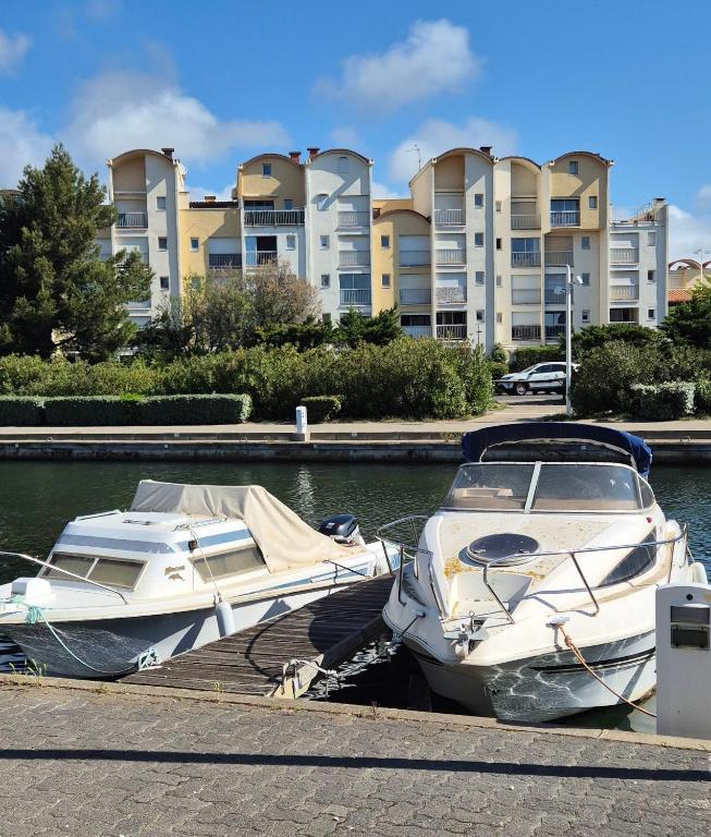 deux bateaux amarrés à un quai devant des condos dans l'établissement Apartment in Port Gruissan, à Gruissan