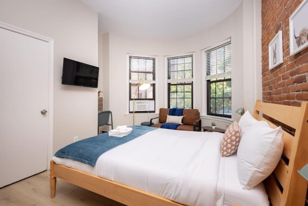 ein Schlafzimmer mit einem Bett und einer Ziegelwand in der Unterkunft Serene Studio with Cozy Atmosphere in Boston