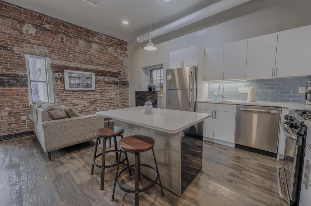 Una cocina con encimera blanca y pared de ladrillo. en Luxury Furnished Loft near Park Street Station, en Boston