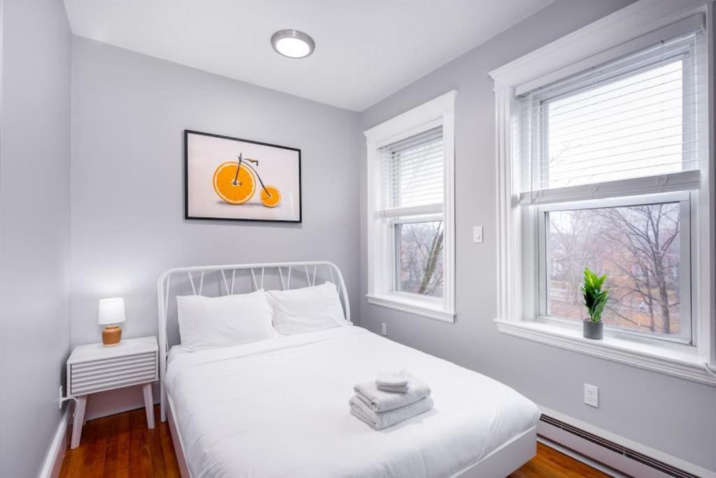 a white bedroom with a bed and two windows at Cozy Central Fenway Studio in Boston