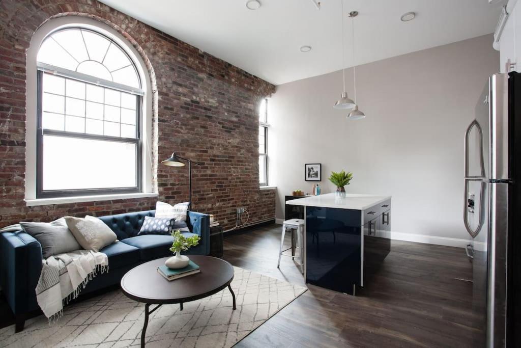 ボストンにある4 bed Loft Steps to Boston Common Beacon Hillのソファとレンガの壁のあるリビングルーム