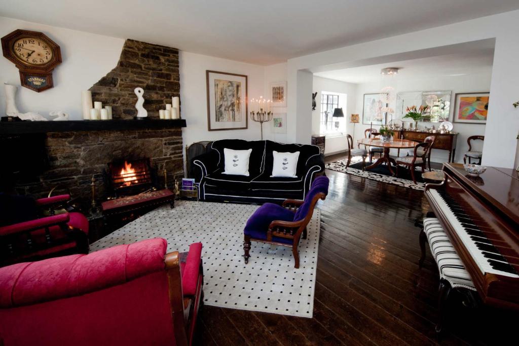 a living room with a fireplace and a piano at The K Kinsale in Kinsale