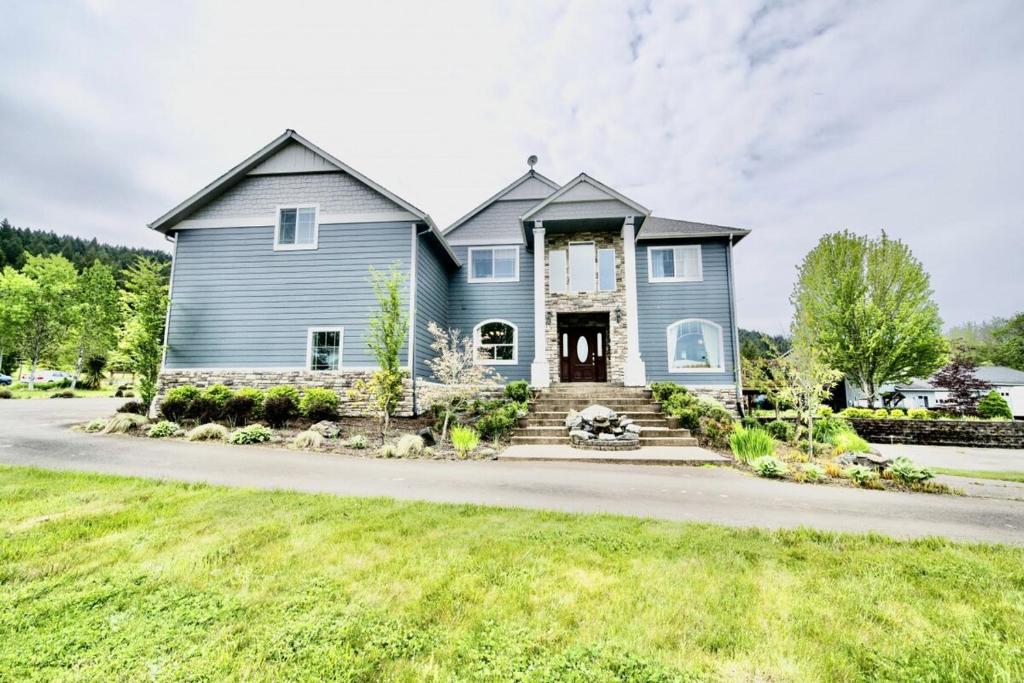 une grande maison bleue avec une allée dans l'établissement PNW Red Tail Ridge, à Philomath