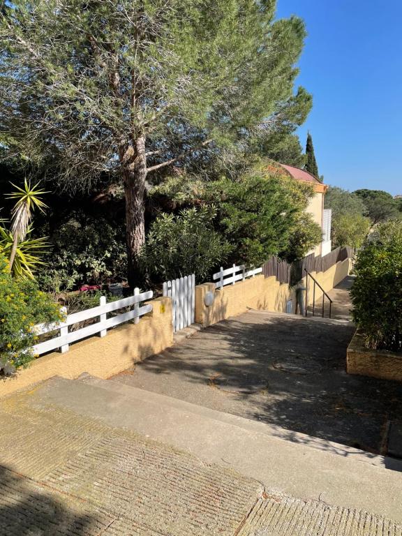 une clôture blanche et un arbre dans une cour dans l'établissement Location maison vacances T3, à Gruissan