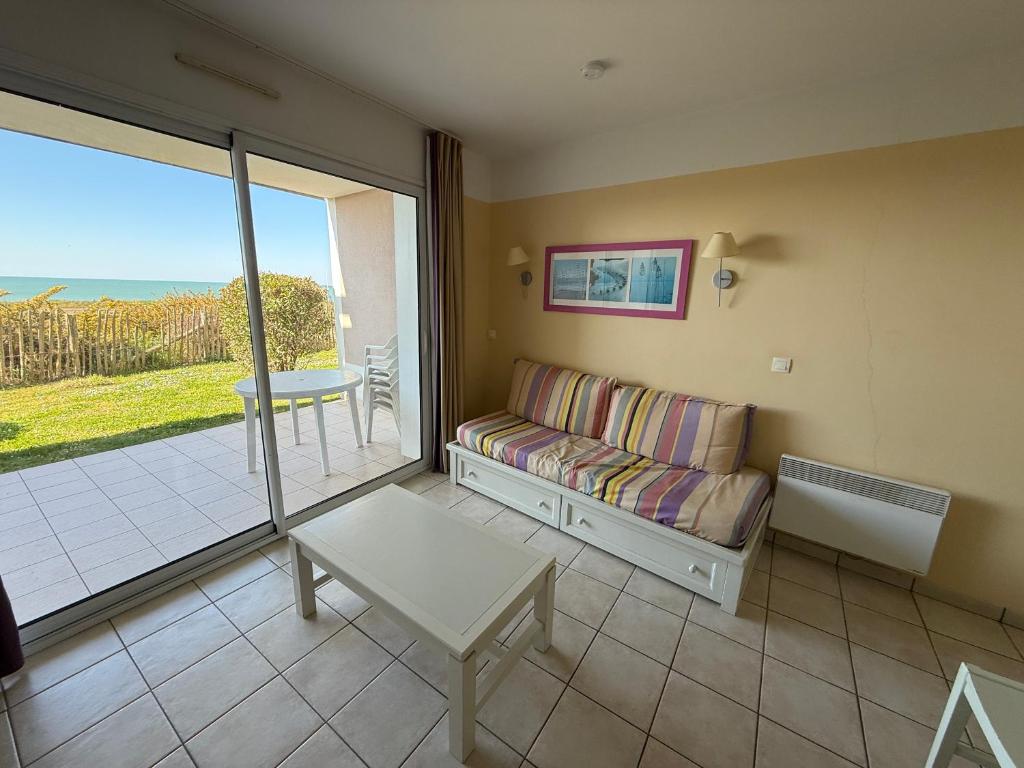 un salon avec un canapé et une vue sur l'océan dans l'établissement Charmant appartement T2 en rez de jardin terrasse face mer 4 personnes, à Les Sables-dʼOlonne
