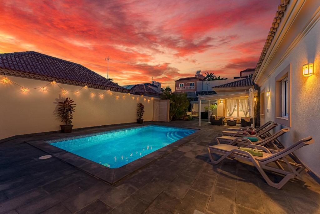 a swimming pool with lounge chairs and a sunset at Villa Jardin del Sol in Adeje