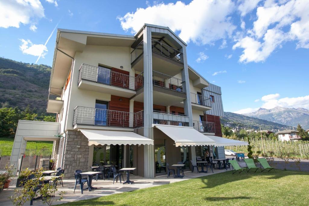 un bâtiment avec des tables et des chaises devant lui dans l'établissement La Bicoque, à Aoste