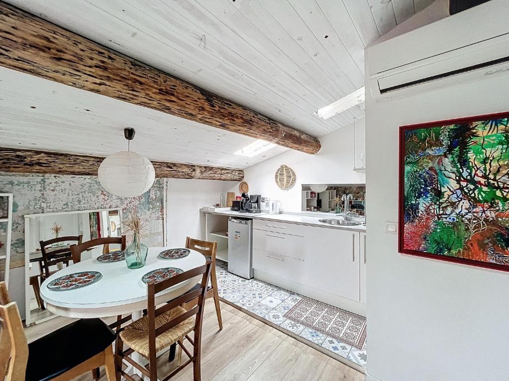 une cuisine et une salle à manger avec une table et des chaises dans l'établissement Charmant appartement dans quartier grand théâtre, à Sète