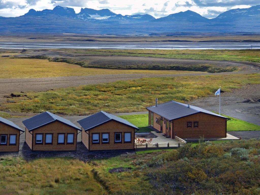 eine Gruppe von Häusern auf einem Feld mit Bergen im Hintergrund in der Unterkunft Fishing Lodge Hálsakot in Sleðbrjótur
