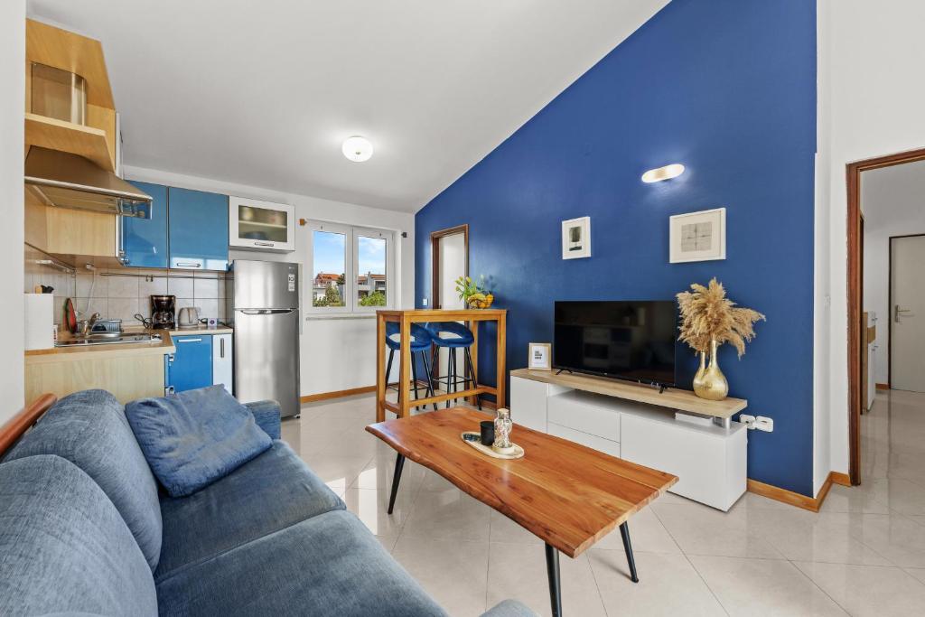 a blue living room with a couch and a table at Apartman Lorena in Fažana