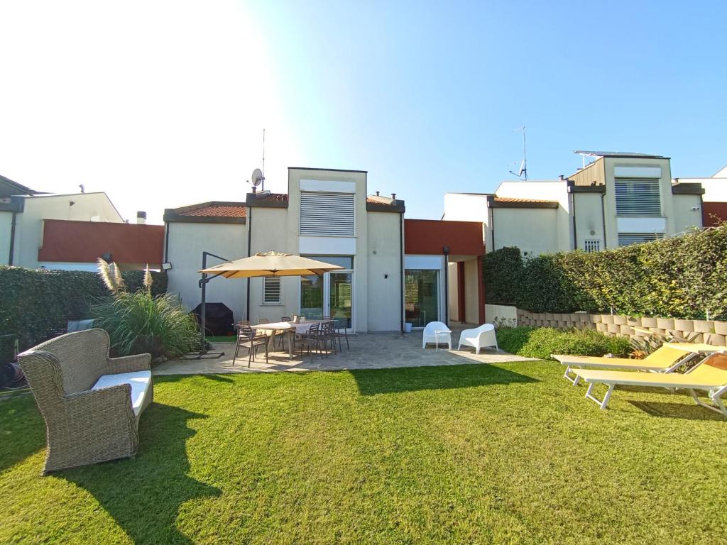 a yard with chairs and tables and an umbrella at SunStyle House Villetta Rimini con Giardino e Park in Casalecchio
