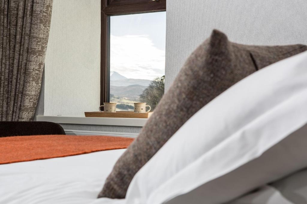 uma cama com uma janela com vista para uma montanha em Bosville Hotel em Portree