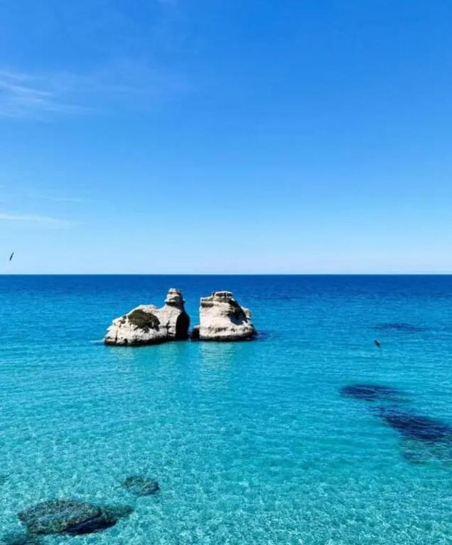 a group of rocks in the ocean with blue water at Casa vacanze Donna VALERIA in San Foca