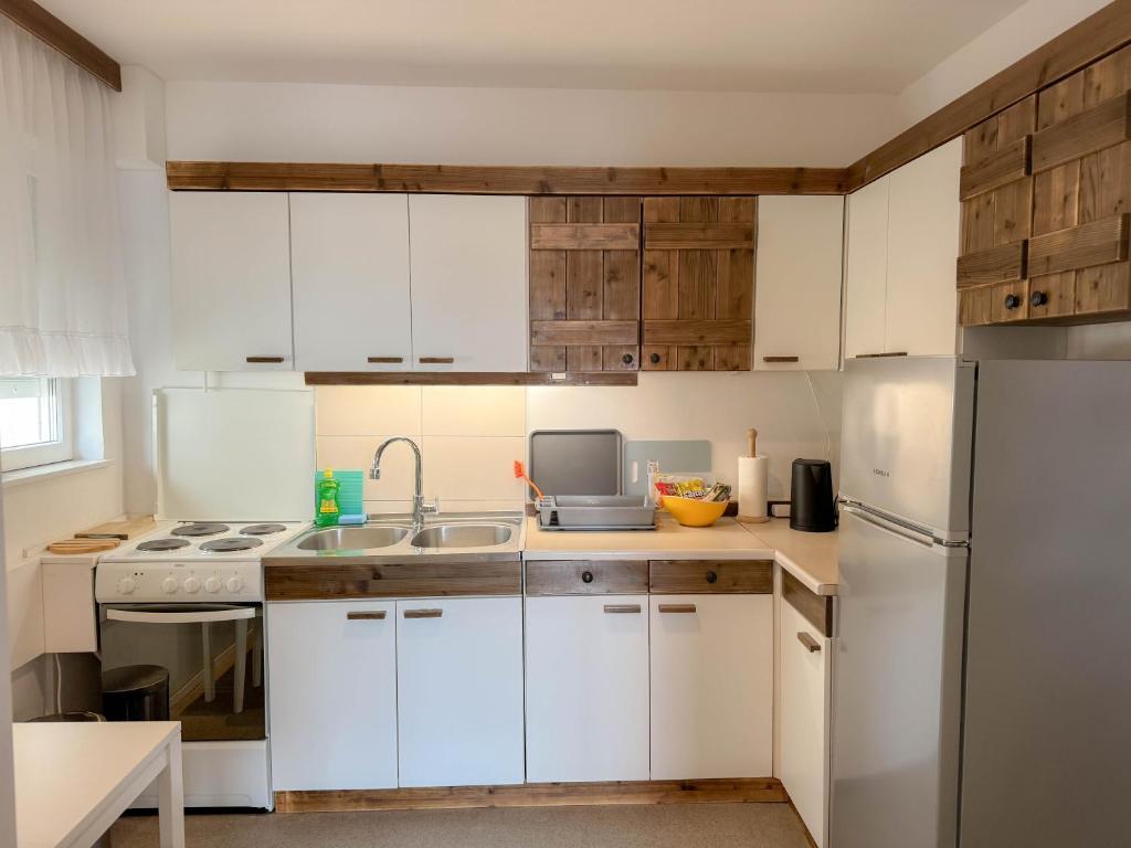 a kitchen with white cabinets and a sink and a refrigerator at Apartment Romeo in Crikvenica