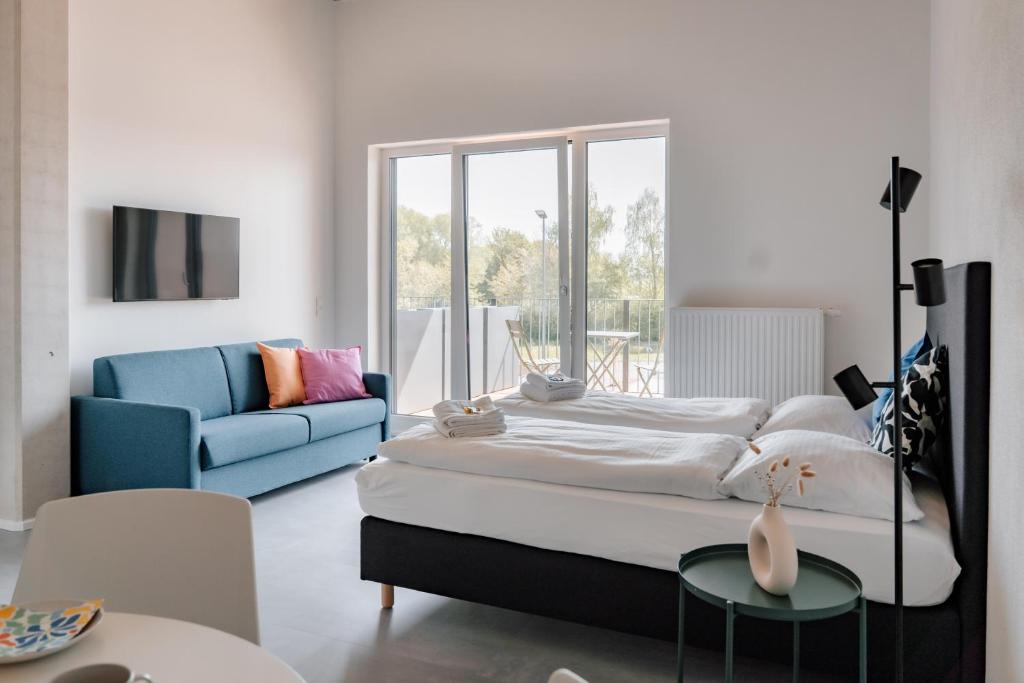 a bedroom with a large bed and a blue couch at Skyrise Apartments - Stilvoll wohnen, entspannt genießen in Bad Wörishofen
