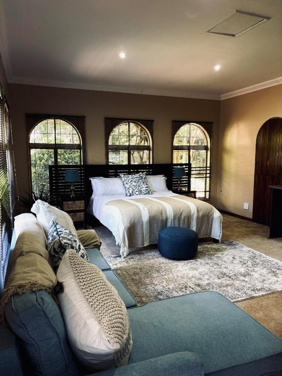 a bedroom with two beds and a couch at Villa Bloemé Guesthouse in Bloemfontein