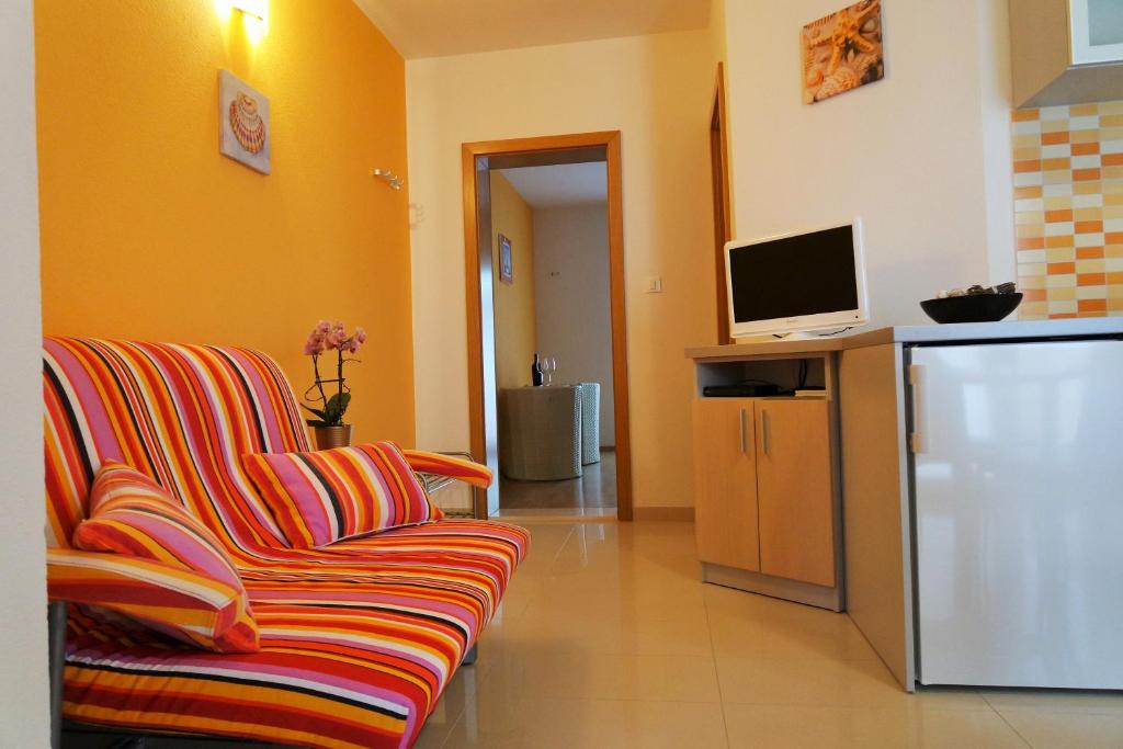 ein Wohnzimmer mit einem Sofa und einem TV in der Unterkunft Apartments Harmonija in Baška Voda