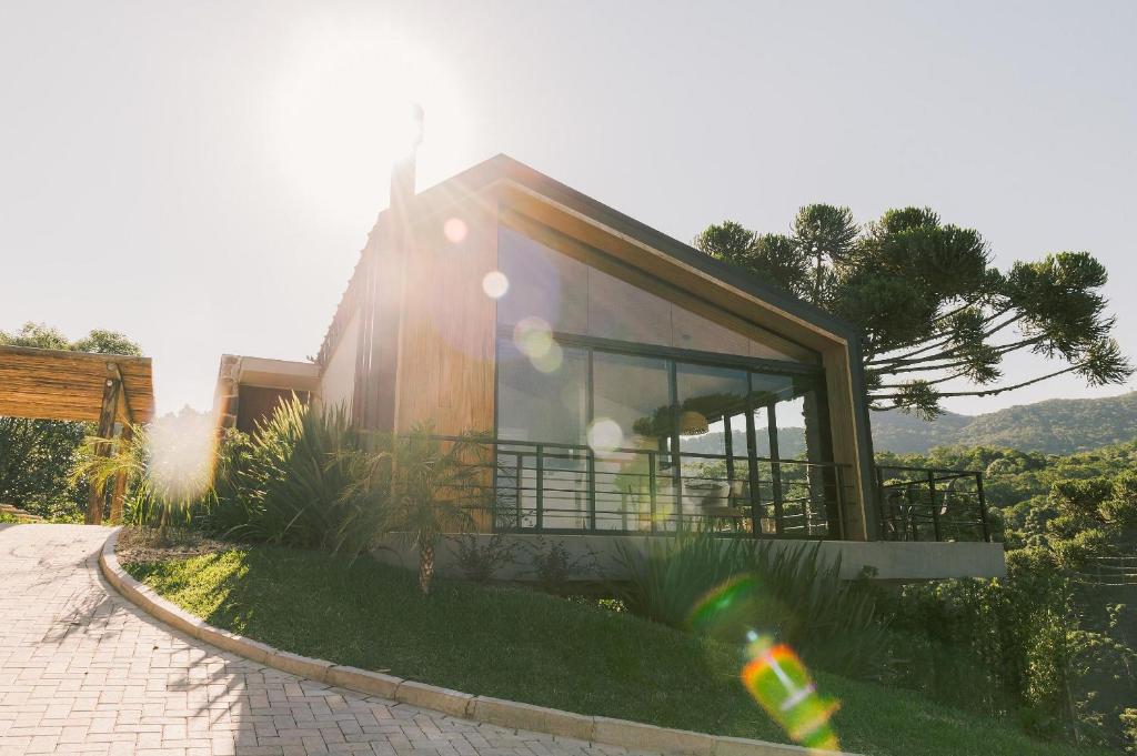 a house on a hill with the sun shining on it at Elegante bangalô de campo 5 - Taquaras Huts in Rancho Queimado