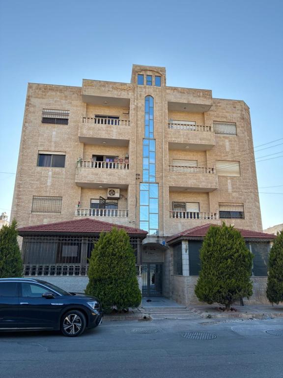 a black car parked in front of a building at Furnished Family Apartment in Dahyet Al-Rasheed in Amman