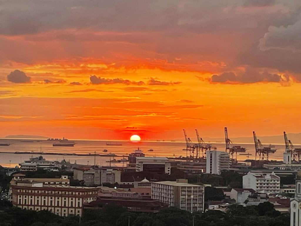 a sunset over a city with buildings and cranes at Condo near Intramuros, Manila in Manila