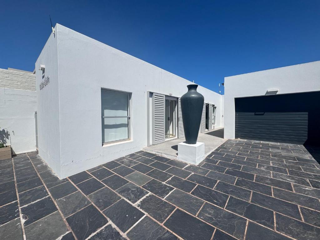 a white building with a large vase on a patio at Carpe Diem in Langebaan