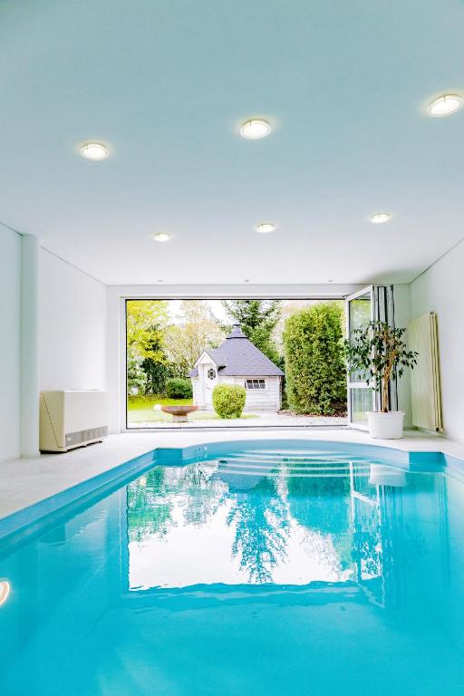 a swimming pool in a house with a large window at Dreamapartment La Vigna "Stone" Suite mit eigenem Indoorpool & Sauna & Grillhütte - Weil am Rhein in Weil am Rhein
