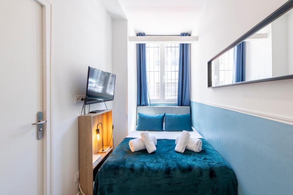 Cette chambre comprend un lit avec des draps bleus et une télévision. dans l'établissement Parisian Getaway for two in iconic Montmartre neighborhood, à Paris