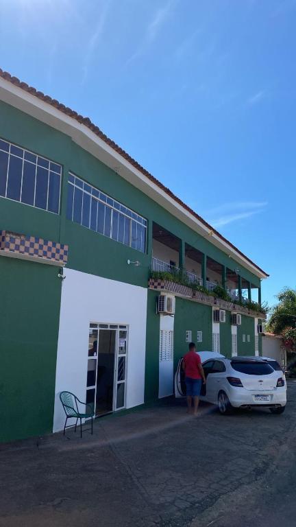 UruaçuHotel Ouro Fino的一名女子站在一栋建筑外，外面停着一辆车
