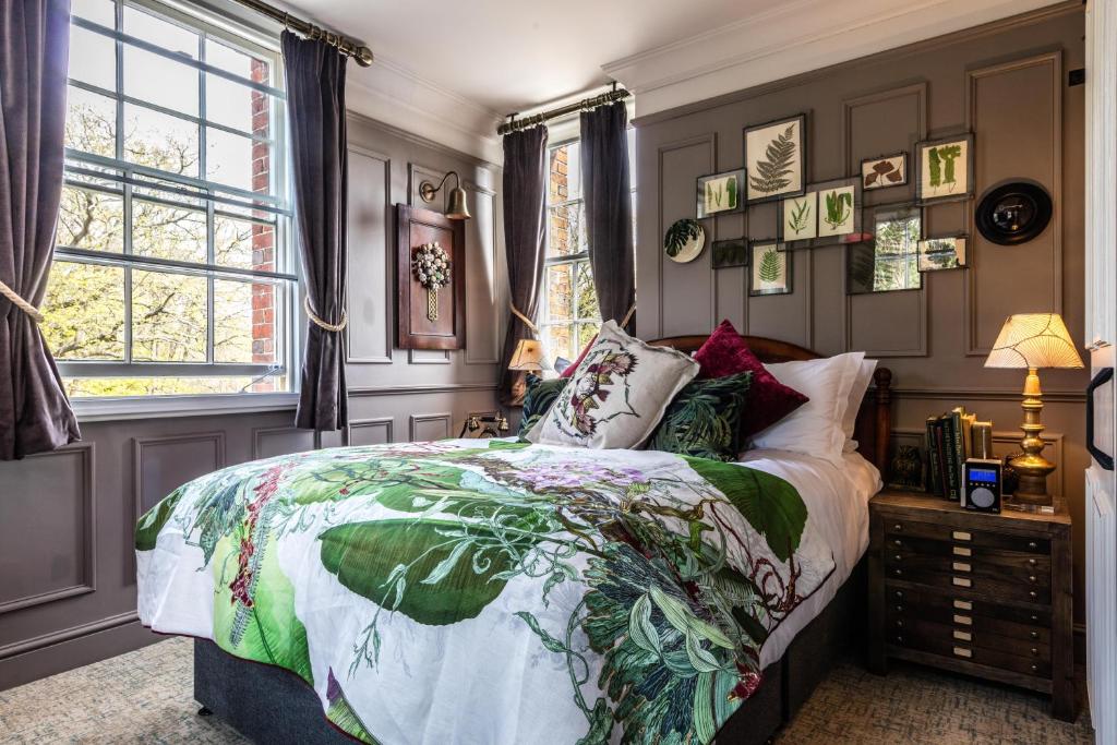 a bedroom with a bed with a colorful comforter and a window at Hand and Spear in Weybridge