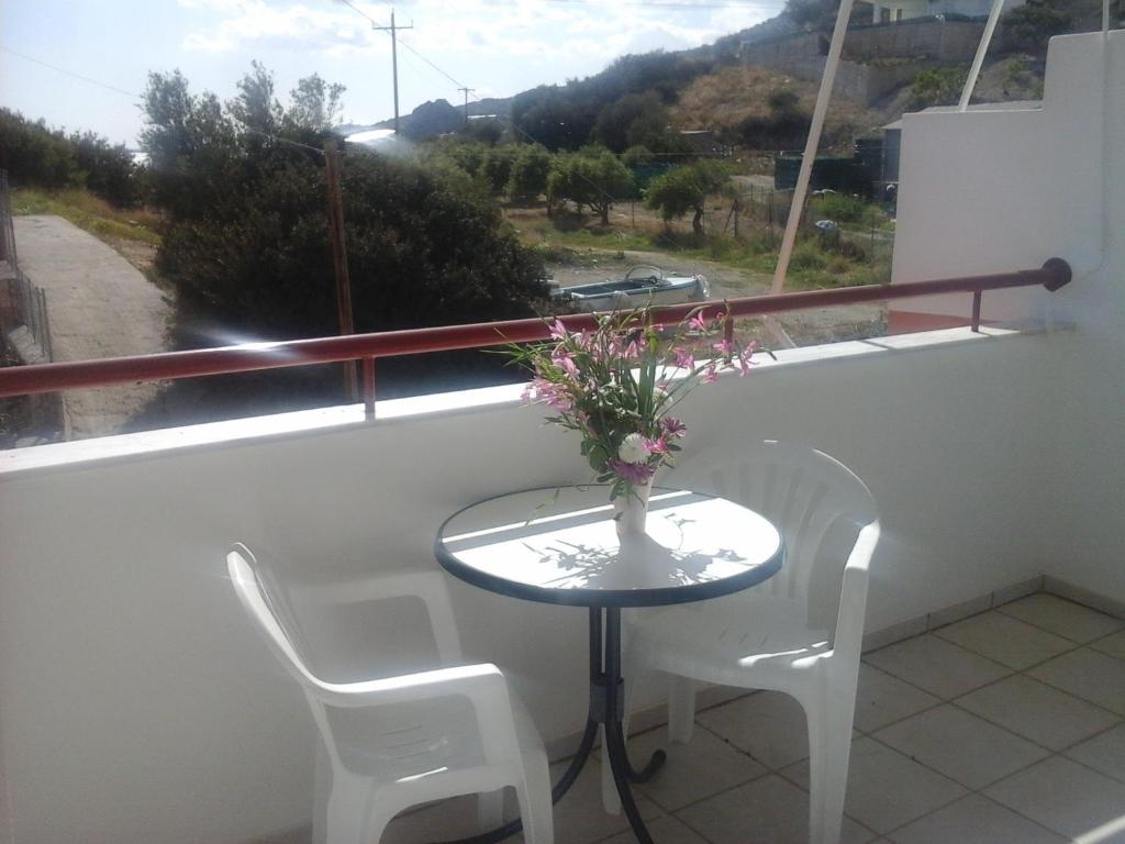 a table with chairs and a vase of flowers on a balcony at Xenos Apartments in Keratokampos