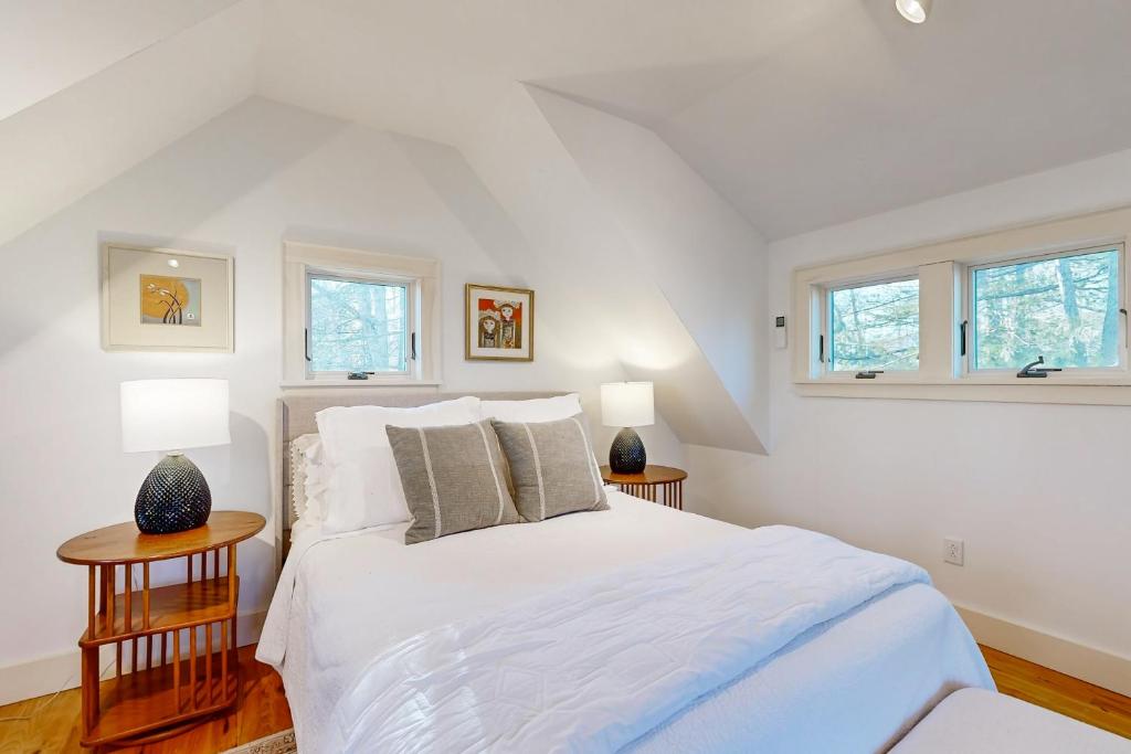 a bedroom with a white bed and two tables at Walker Cottage in Rockport