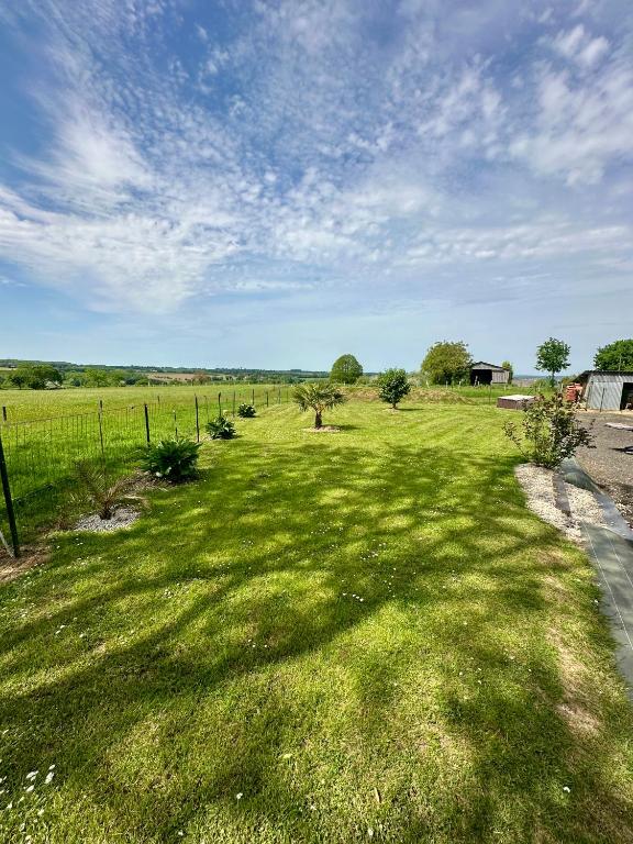 un champ d'herbe avec une clôture et un ciel dans l'établissement Gîte près du Mont Saint Michel 8 à 10 pers, à Saint-Senier-de-Beuvron