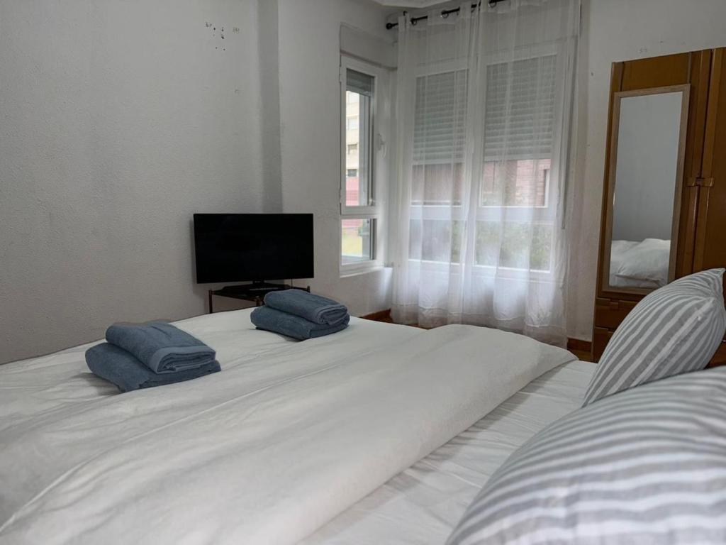 a bedroom with a large white bed with two blue pillows on it at Entire apartment centro ponferrada in Ponferrada