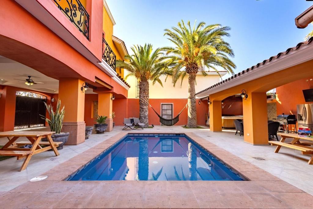 une piscine devant une maison avec des palmiers dans l'établissement La Posada Alberca privada y playa cercana, à La Paz