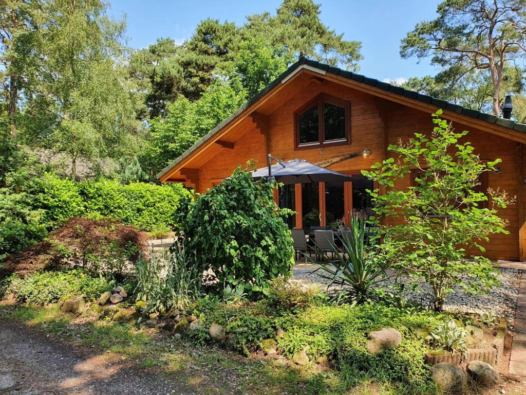 a wooden house with an umbrella in front of it at Villa in Forest with Private Sauna in Markelo