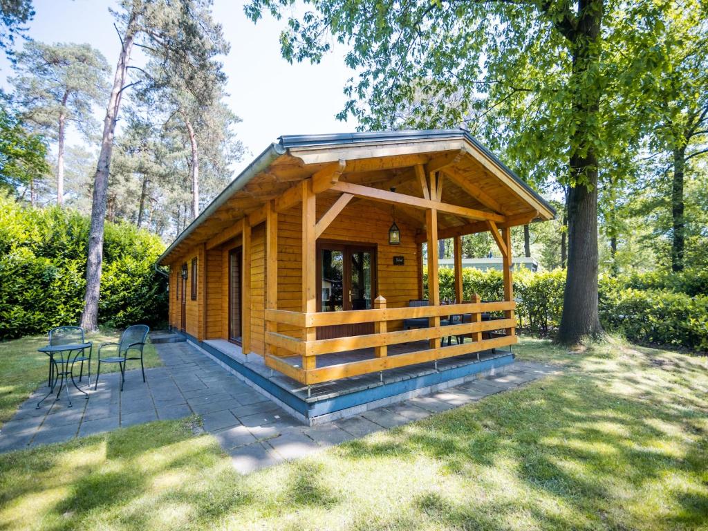 Cabaña de madera con mesa y sillas en un patio en Lodge in Markelo with Sauna and Pool Nearby, en Markelo
