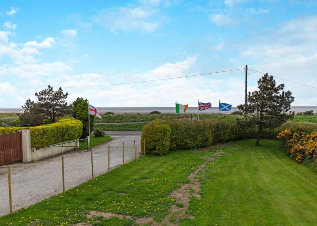 a yard with flags on the side of a road at Rowanbank Caravan Park in Beckfoot