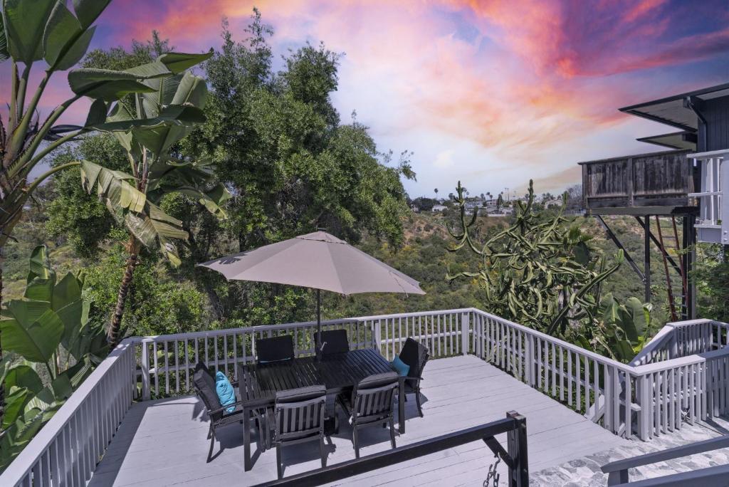 a deck with a table and chairs and an umbrella at Near All Things SD - Canyonview - Jacuzzi - EV Charge in San Diego